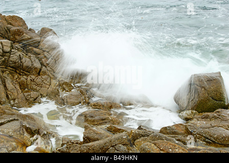 Eau gelée dans l'action d'une vague se brisant sur les rochers. Banque D'Images