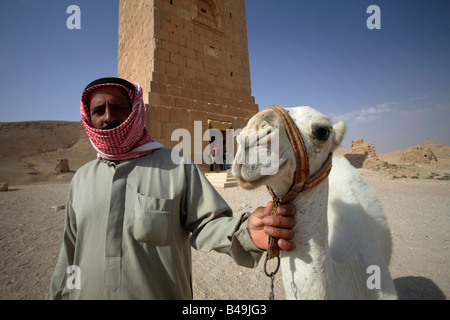 Homme avec camel en avant du tours funéraires romaines dans la vallée des tombeaux, Palmyra, Syrie Banque D'Images