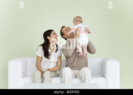 Les parents assis ensemble sur canapé, man holding baby Banque D'Images