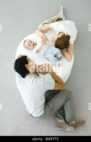 Les parents et le bébé se détendre sur un pouf, baby holding mother's hand, overhead view Banque D'Images