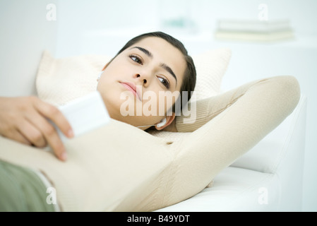 Jeune femme couchée sur le dos, listening to MP3 player