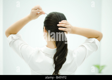 La mise en queue de cheveux Femme, bras levés, vue arrière Banque D'Images