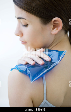 Femme plaçant compresse froide sur l'épaule, close-up Banque D'Images