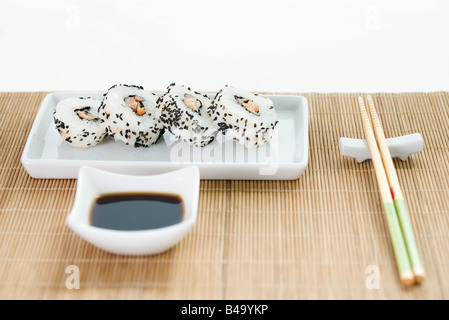 Maki sushi avec de la sauce soja et de baguettes en bambou disposés sur napperon Banque D'Images