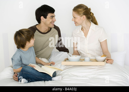 Père et fils mère donnant le petit déjeuner au lit Banque D'Images