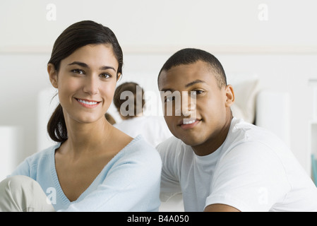 Couple smiling at camera, tout-petit en arrière-plan Banque D'Images