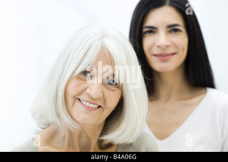 Mère et sa fille adulte Senior smiling at camera, focus on foreground Banque D'Images