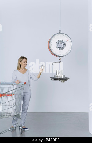 Femme debout avec panier, placer les boîtes sur l'échelle Banque D'Images