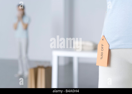 Close-up de vente tag sur shirt, femme debout en arrière-plan Banque D'Images