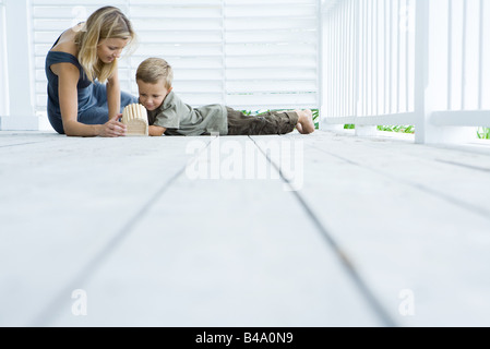 La mère et le fils assis sur le plancher du porche à la volière à Banque D'Images