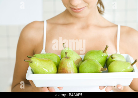 Woman holding plate of poires vertes, close-up Banque D'Images