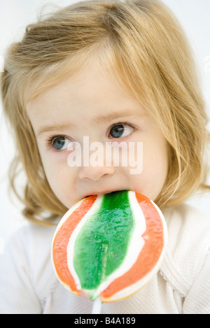 Girl eating grande sucette, looking away Banque D'Images