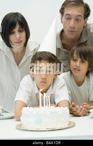 L'observation de la famille garçon souffler les bougies sur le gâteau d'anniversaire Banque D'Images
