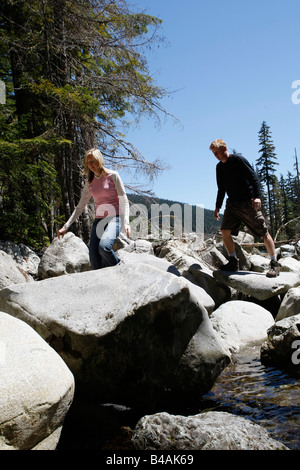 Couple hiking sur des rochers au bord d'une rivière pendant une randonnée dans la région de Whistler BC Banque D'Images