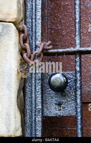 Rusty porte verrouillée à une crypte protégée par une porte de barres noires verrouillé et enchaîné fermée. Banque D'Images