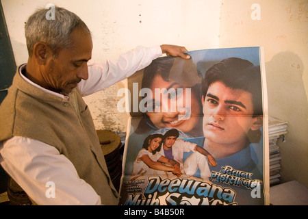 Un homme est titulaire d'une affiche de film de Bollywood dans un distributeurs de films en Varanasi, Inde. Banque D'Images