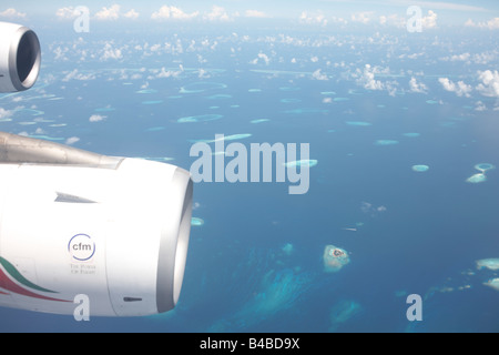 Un bleu océan Indien et atolls éloignés dans la République des Maldives sont bien en dessous de l'aile d'un Airbus de port et moteurs CFM Banque D'Images