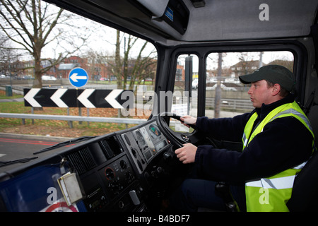 Porter un haut-vis tabard et une casquette, un jeune conducteur est assis au volant de son camion poids lourds sur l'A3 Trunk Road à Londres Banque D'Images