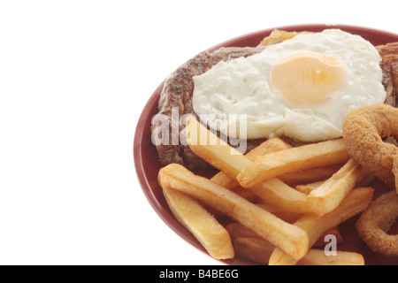 Faux Filet de boeuf frais Steak AVEC UN Œuf frit, des oignons et des frites contre un fond blanc isolé avec aucun peuple et un chemin de détourage Banque D'Images