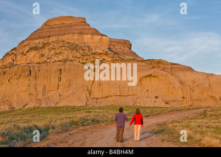 Couple en train de marcher le long de la route vers Castle Butte au coucher du soleil dans les Big Muddy Badlands, dans le sud de la Saskatchewan, Canada Banque D'Images