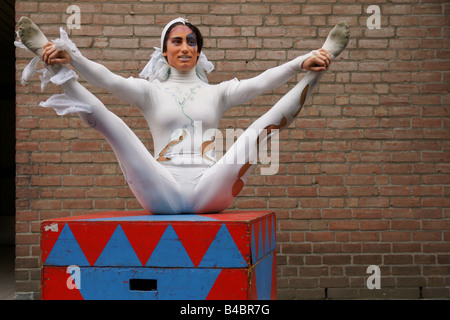 Jeune femme italienne souple clown contorsionniste montrent l'exécution de tout le corps plié face à l'un sourire à l'extérieur des jambes propagation circus Banque D'Images