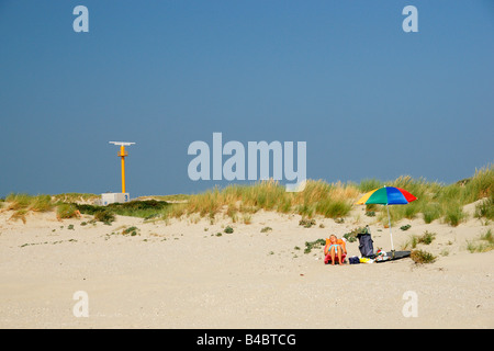 Femme de profiter du soleil assis sous parapluie parasol coloré plage sable mer vacances d'Hoek van Holland Pays-Bas Banque D'Images