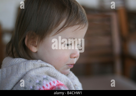 A 17 mois bébé fille regarde vers le bas. Banque D'Images