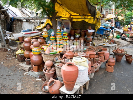 Une indienne en sari vente de faïence et des légumes dans une échoppe de marché à l'extérieur de son refuge hut et salle de stockage. Banque D'Images