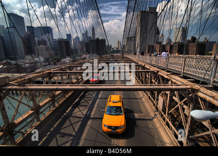 Un taxi est parmi le trafic traversant le pont de Brooklyn. Les piétons peuvent également être vu sur la passerelle supérieure.