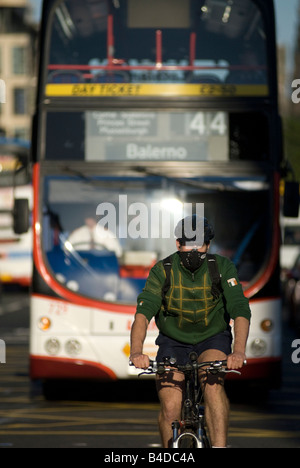 Un cycliste masqué sur Princes Street d'Édimbourg, le vélo en avant d'un bus de transport régional de Lothian Banque D'Images