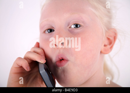 Tête et épaule rapprochée sur une petite blonde aux cheveux bruns, blue-eyed girl parler sur un téléphone cellulaire/mobile Banque D'Images