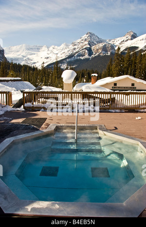 Contraste d'hiver rempli de l'eau piscine extérieure avec personne entouré par la neige avec les immeubles et les montagnes en arrière-plan Banque D'Images