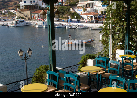 Tables et chaises vides en taverne surplombant le port et la ville de Batsi Andros île de Cyclades Grèce Banque D'Images