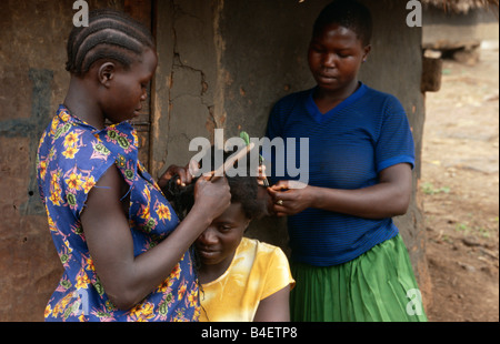 Les femmes engagées dans la coiffure les uns les autres dans le village. L'Ouganda. Banque D'Images