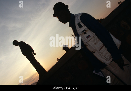 Deux hommes, l'un portant chapeau melon, travaillant sur des projets d'eau au coucher du soleil, la silhouette du portrait, le Rwanda, l'Afrique Banque D'Images