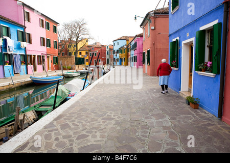 Femme mature multicolore marche dans une rue à l'île de Burano Italie Venise Banque D'Images