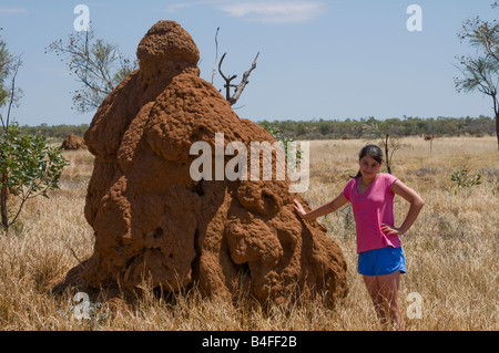 Jeune fille debout à côté d'un grand nid de termites pour montrer l'échelle près de Fitzroy Crossing dans la région de Kimberley, de l'Australie Occidentale Banque D'Images