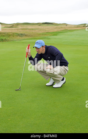 Golfeur professionnel alignement d'un putt sur le green (partie d'une série) Banque D'Images