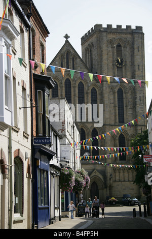 Ville de Ripon, en Angleterre. Kirkgate Street boutiques avec l'ouest avant de l'Église d'Angleterre Ripon cathédrale en arrière-plan. Banque D'Images