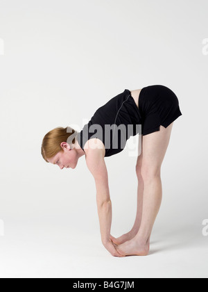 Une jeune femme pratiquant la "flexion avant vers le haut' yoga pose Banque D'Images