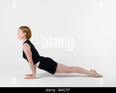 Une jeune femme pratiquant le 'Cobra' yoga pose Banque D'Images