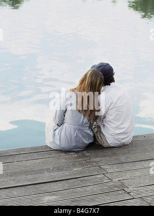 Un jeune couple assis sur une jetée, vue arrière Banque D'Images