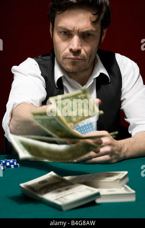 Un homme d'injecter de l'argent dans le pot au jeu de poker High Stakes Banque D'Images
