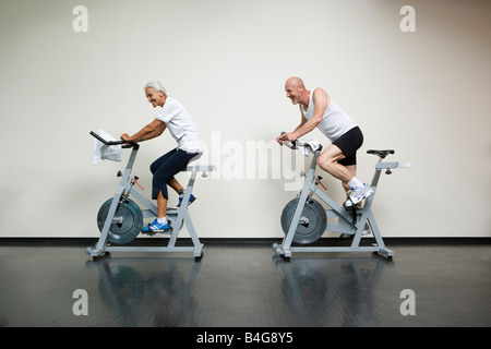 A senior woman et un homme mûr équitation vélos stationnaires Banque D'Images