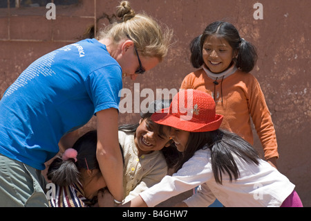 Une femme visite du village touristique se fait des amis avec les enfants en jouant 'rugby' avec eux. Banque D'Images