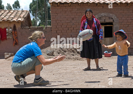 Une femme visite du village touristique se fait des amis avec les enfants en jouant 'rugby' avec eux. Banque D'Images