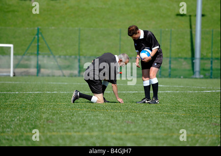 Deux répondants inspecter le terrain de gazon astro avant un match de football. Banque D'Images