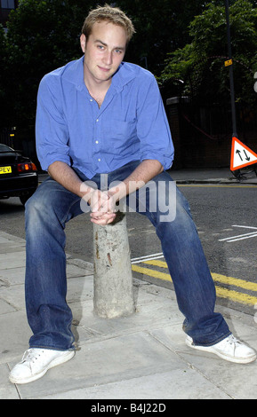 Chris Oliver acteur vu ici se détendre avant le début du tournage d'une nouvelle série de fiction pour Carlton TV blue jeans en denim Shirt White formateurs assis sur trottoir Juillet 2004 Mirrorpix Mirrorpix Banque D'Images