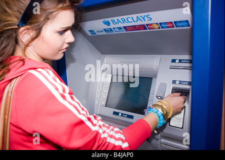 Teenage girl at a cash machine Banque D'Images