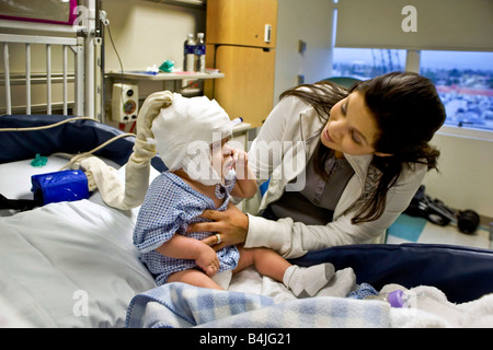 Dans un hôpital de Californie une mère prend soin de son bébé souffrant de moelle bifida Remarque condition monitoring EEG cap Banque D'Images